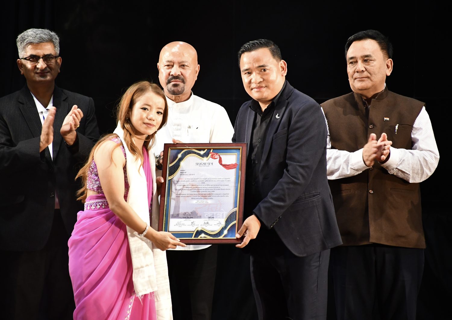Amrita Rai receiving a formal certificate of appreciation from community leaders