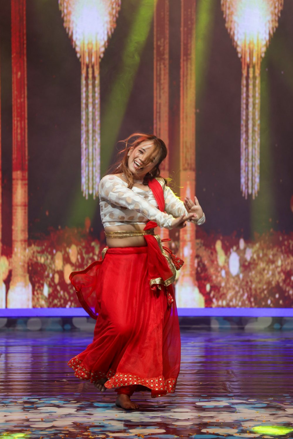 Amrita Rai mid-twirl in a red lehenga during a Bharatanatyam performance