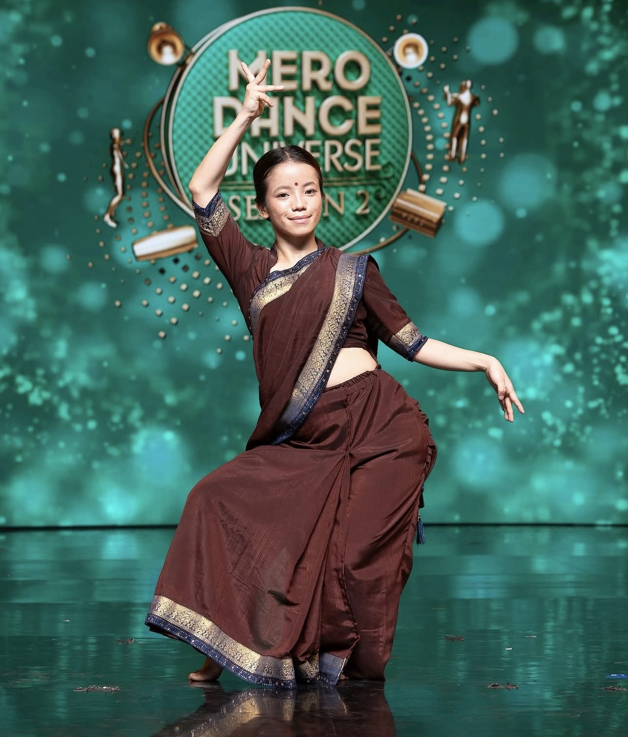 Amrita Rai performing an open style piece in a traditional brown and gold saree at Mero Dance Universe Season 2